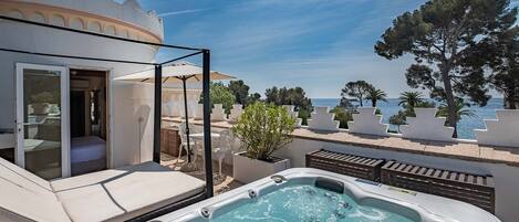 A rooftop terrace with a hot tub, outdoor seating, and a view of the sea.