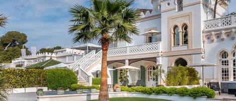 Un edificio imponente con un patio central, palmeras y una escalera que conduce a niveles superiores.