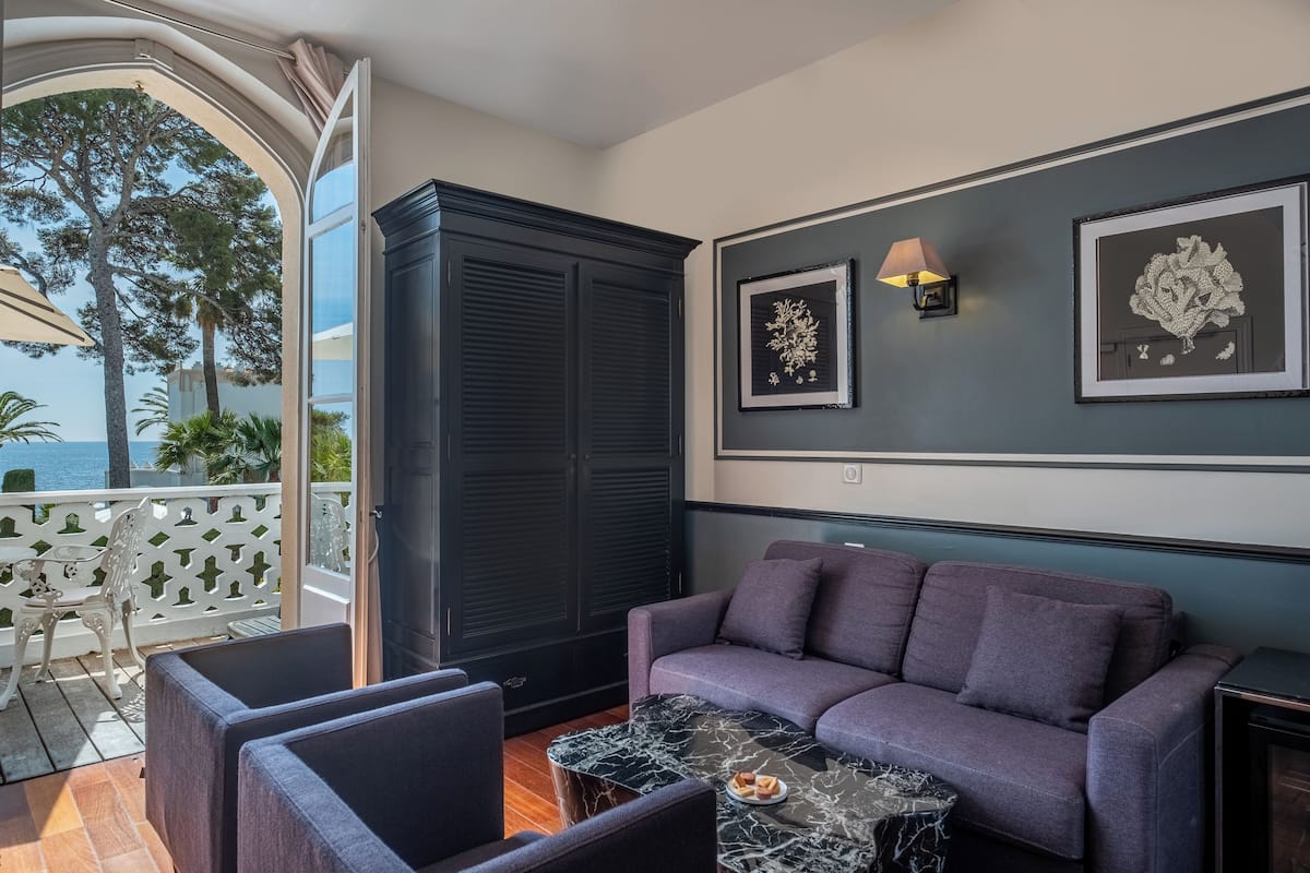 A modern living room with a dark-colored sofa, a marble coffee table, and two framed artworks on the wall.