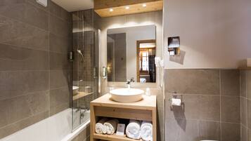 A modern bathroom with a bathtub, a glass-enclosed shower, a wooden vanity with a sink, and a toilet.