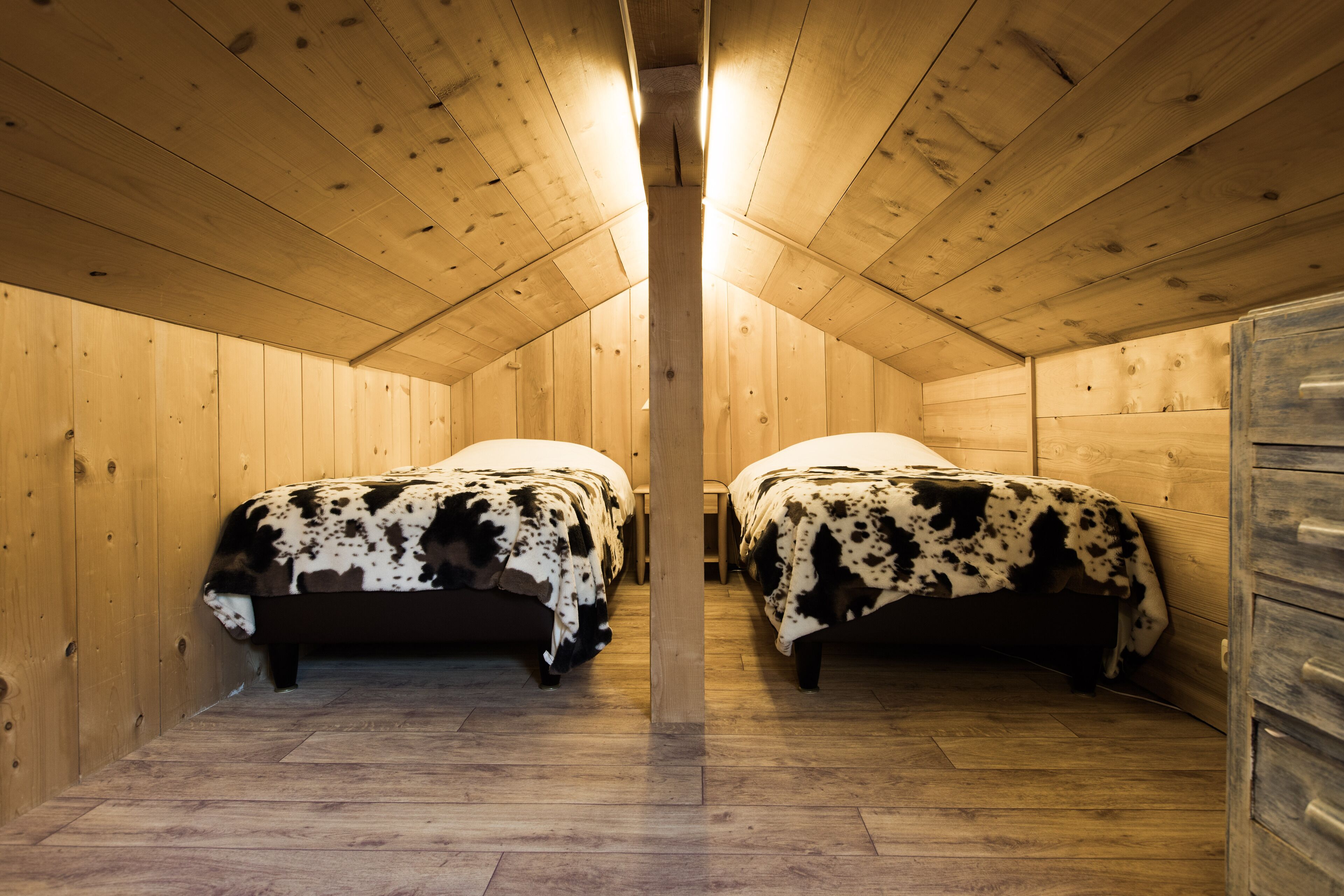 Una cabaña con dos camas, paredes y piso de madera.