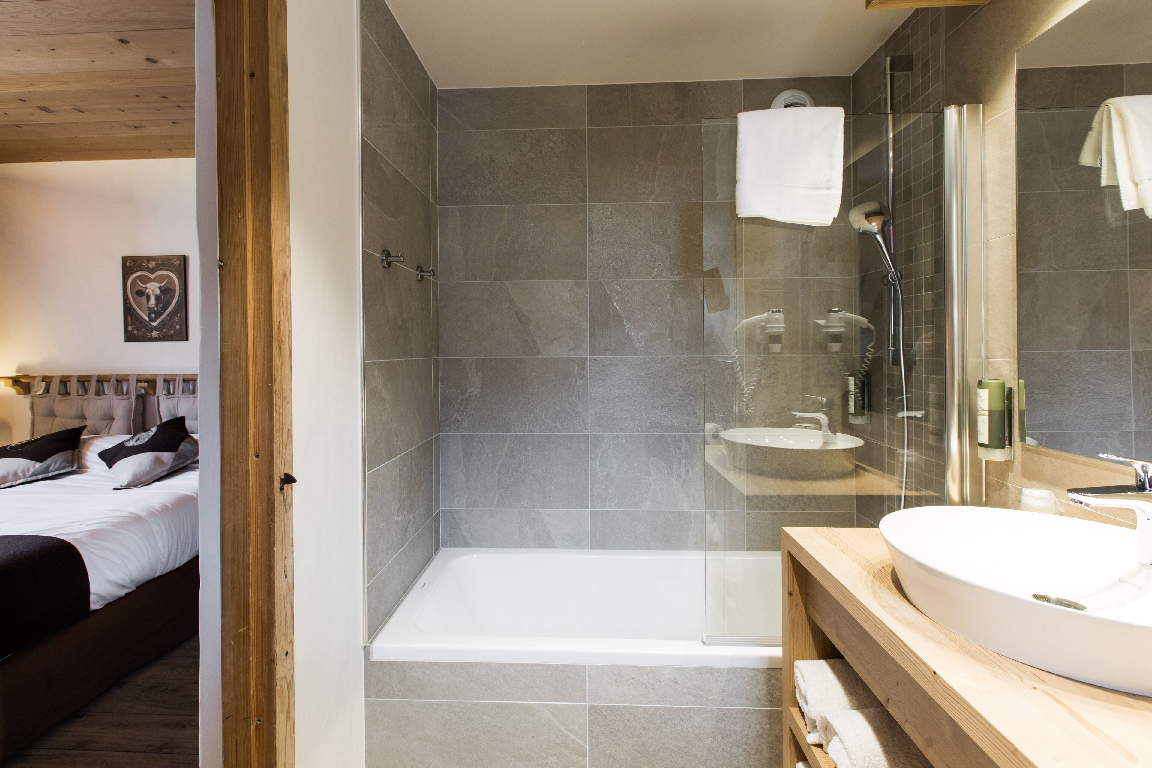 Un baño moderno con ducha envuelta en vidrio, tocador de madera y un espejo grande.