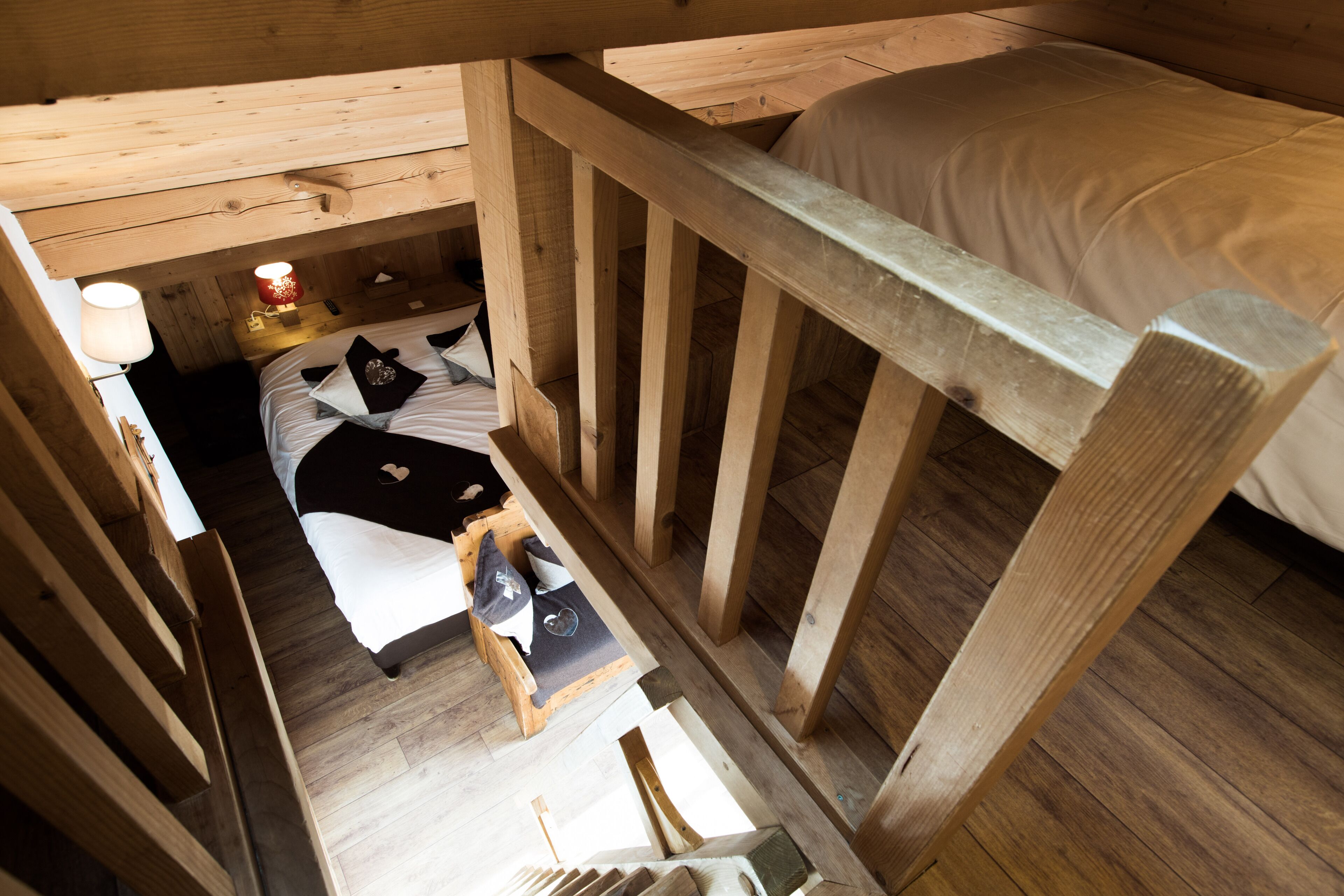 A wooden cabin room with a bunk bed, a small bedside table with a lamp, and a wooden ladder.