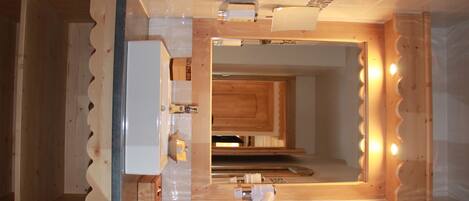 A modern bathroom with a wooden vanity, a mirror, and a shower area.