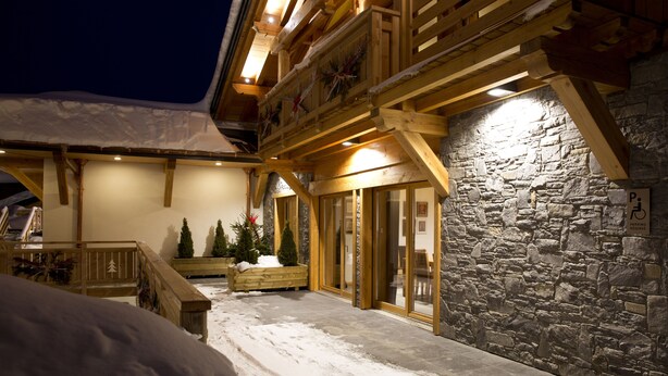 A snow-covered outdoor area with wooden benches and potted plants. - Hôtel La Griyotire (Praz-sur-Arly)