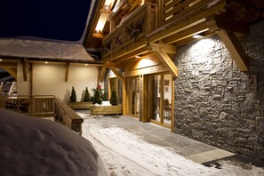 A snow-covered outdoor area with wooden benches and potted plants. - Hôtel La Griyotire (Praz-sur-Arly)