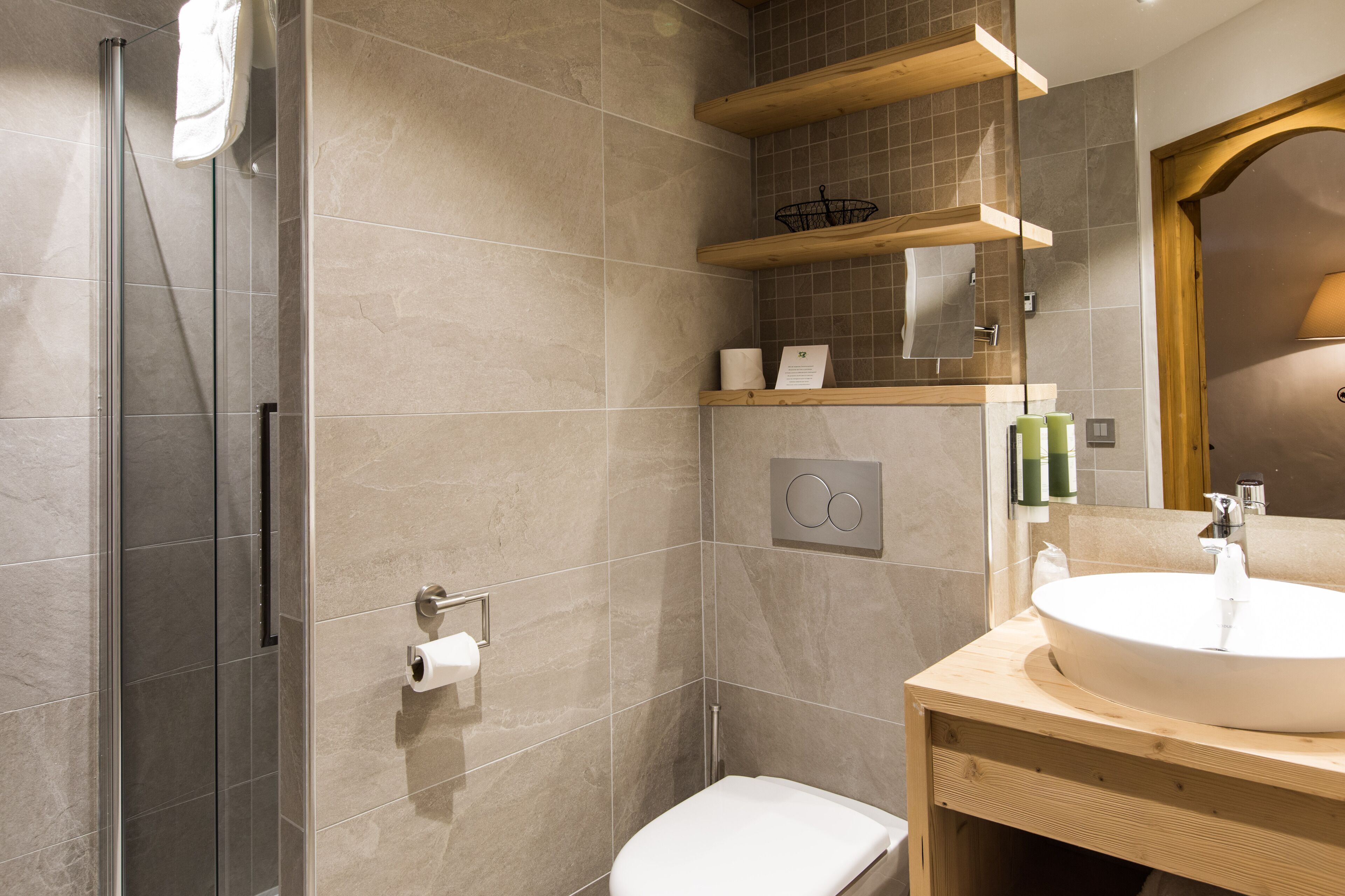Ein modernes Badezimmer mit Duschkabine aus Glas, einem Holzwaschtisch mit Waschbecken und einer Toilette.