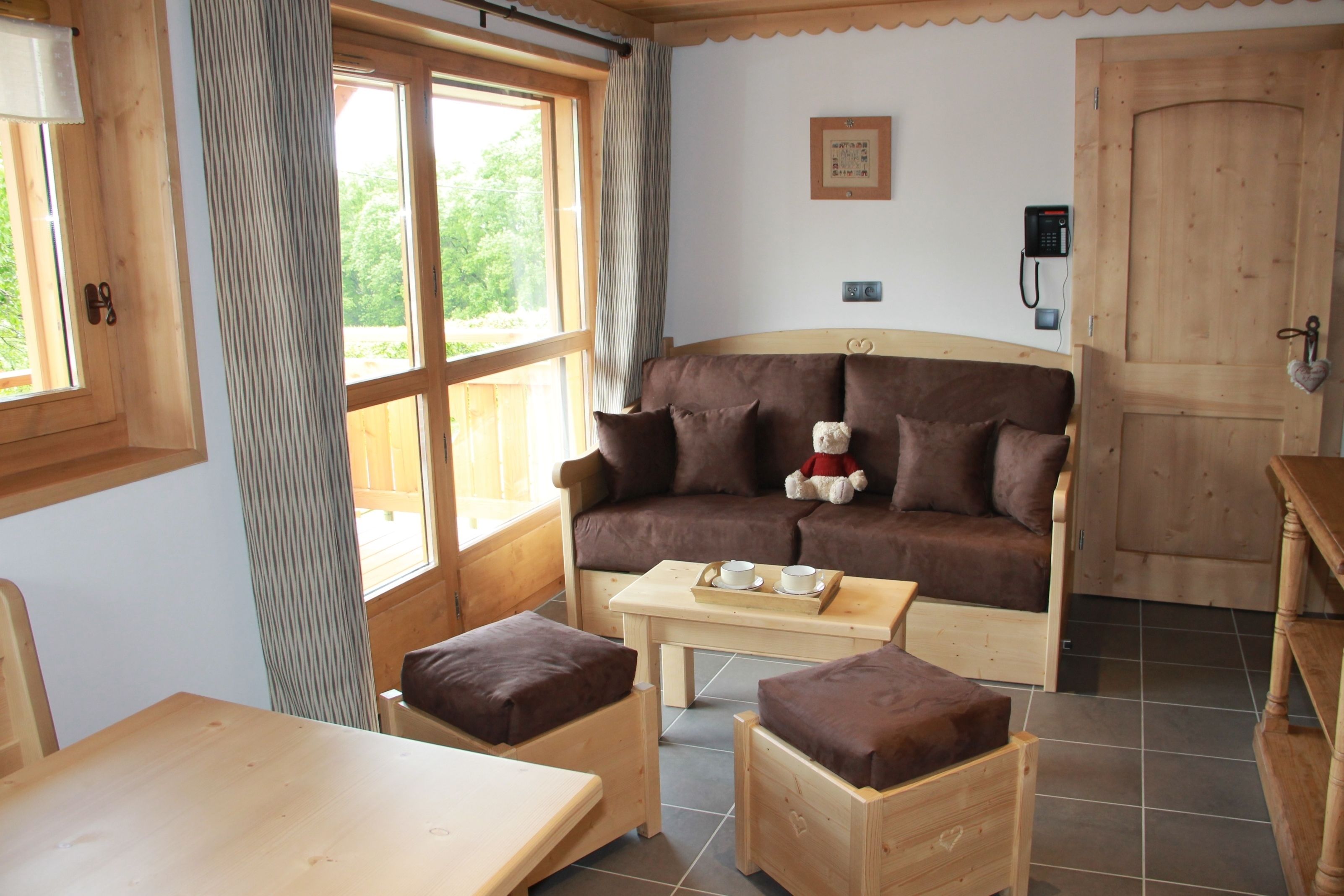 A cozy room with a brown sofa, a wooden table, and two matching ottomans.