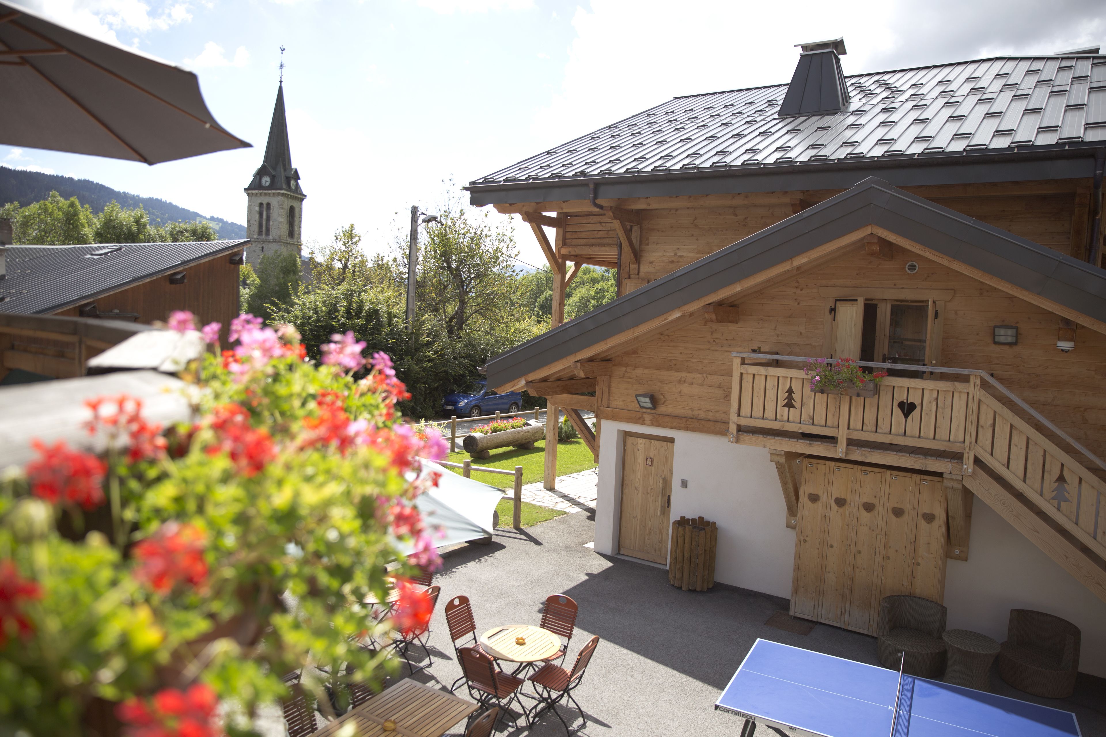 A wooden building with a balcony, a table with chairs, and a ping pong table.