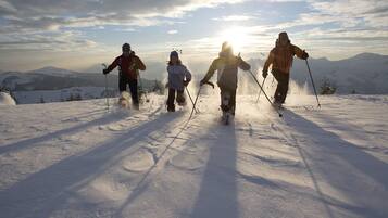 Cuatro personas esquiando de fondo en una montaña nevada bajo un cielo despejado.