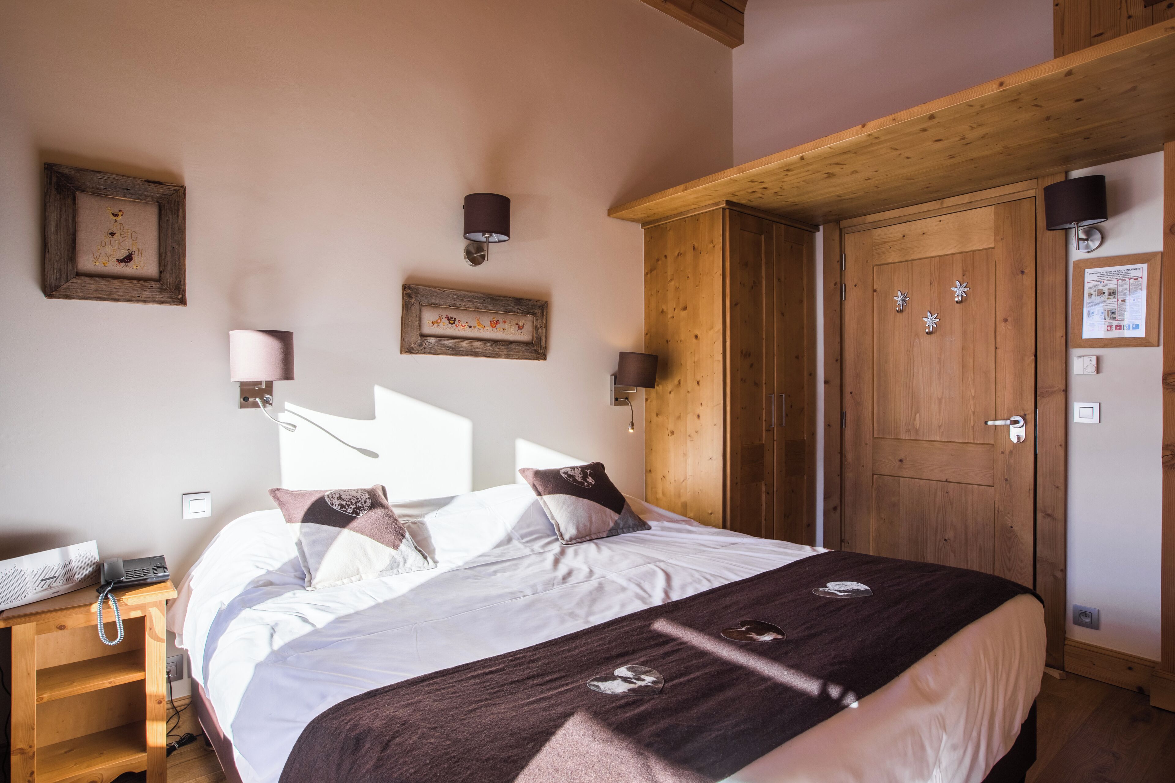 Una camera da letto con un'armadietto in legno, un letto con biancheria bianca e lampade a parete.