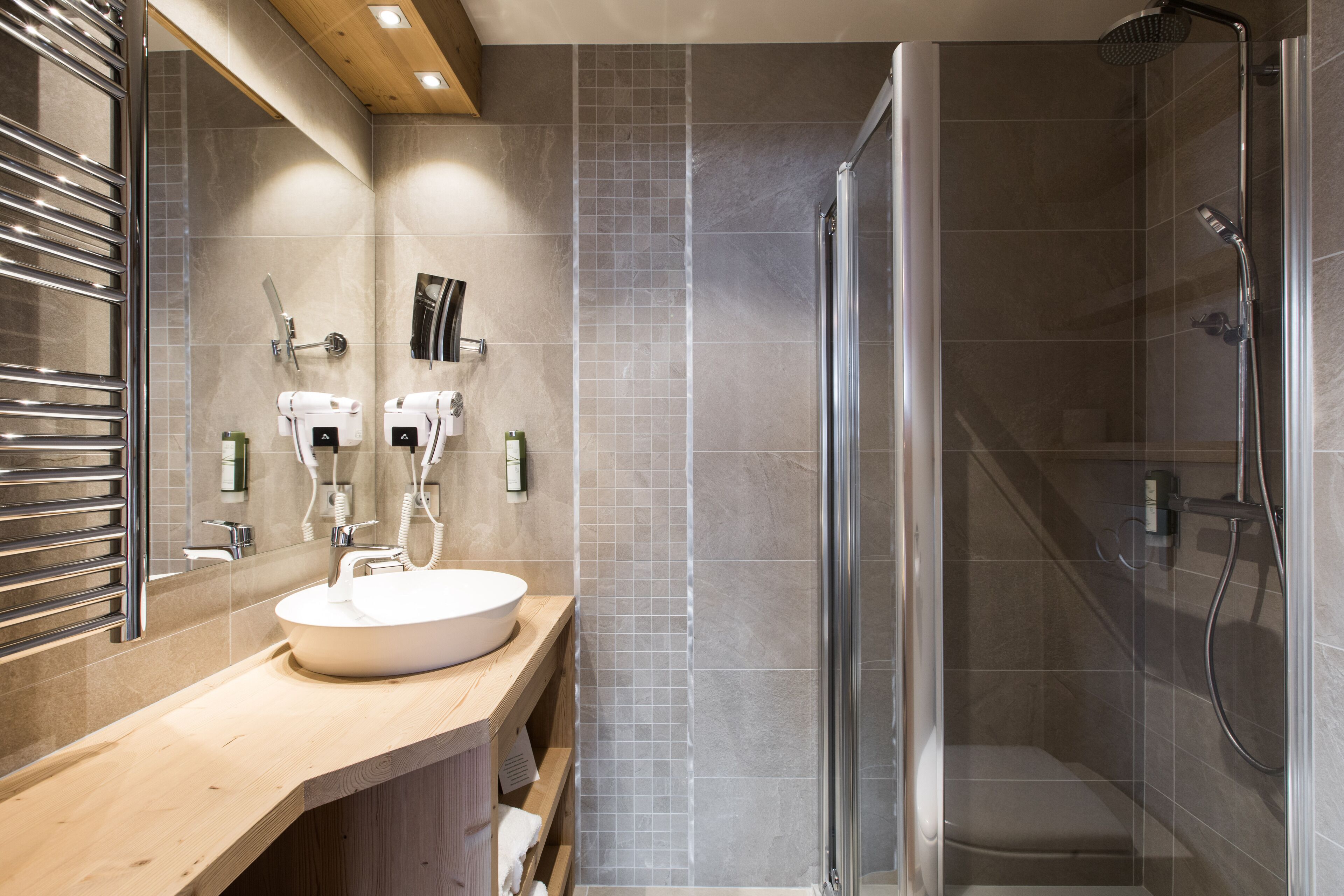 Une salle de bain moderne avec une douche à parois de verre, un meuble-lavabo en bois et un grand miroir.