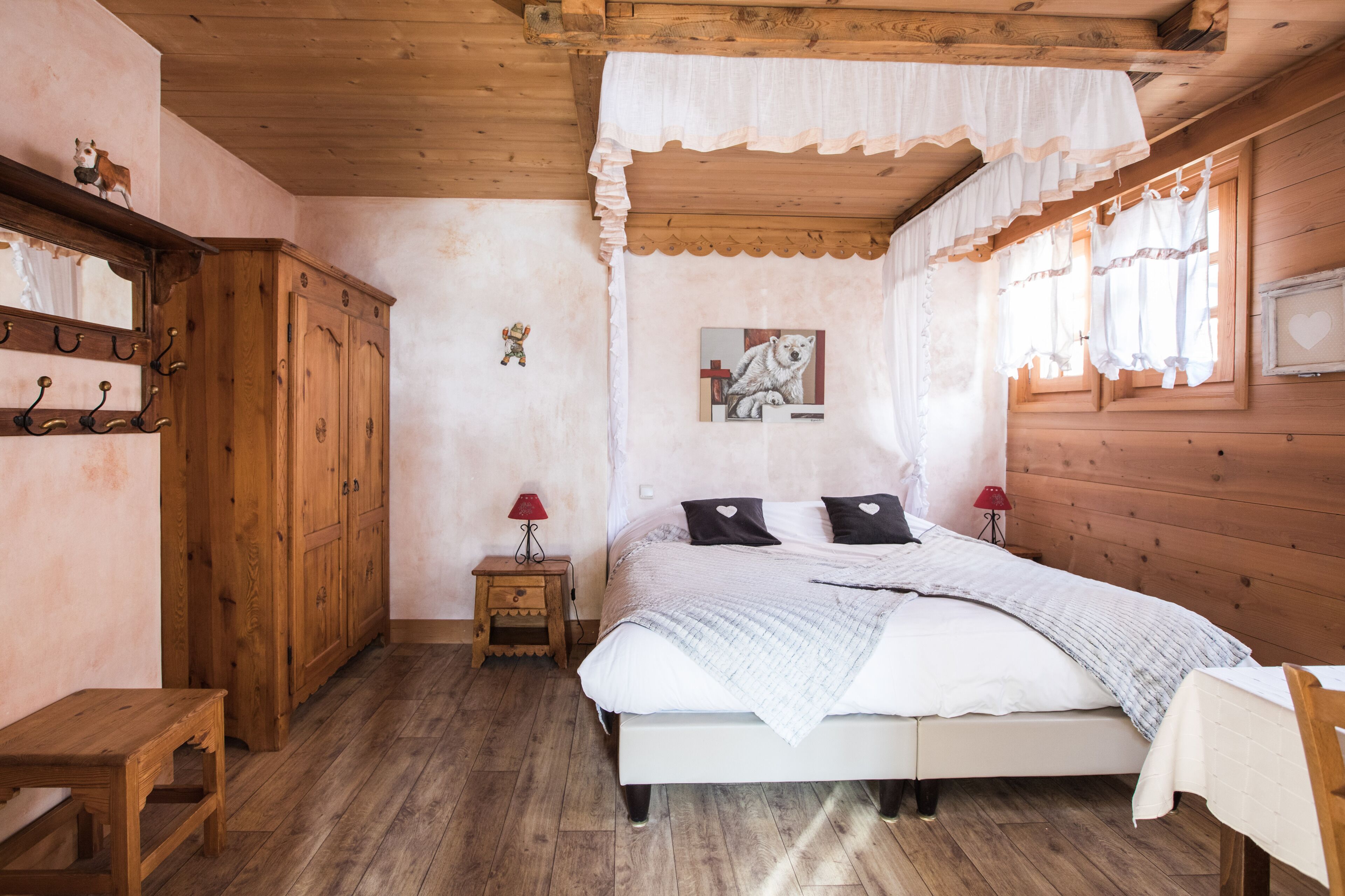 Une chambre à coucher dans un chalet en bois, avec un lit, une table de chevet, une petite table et une armoire.