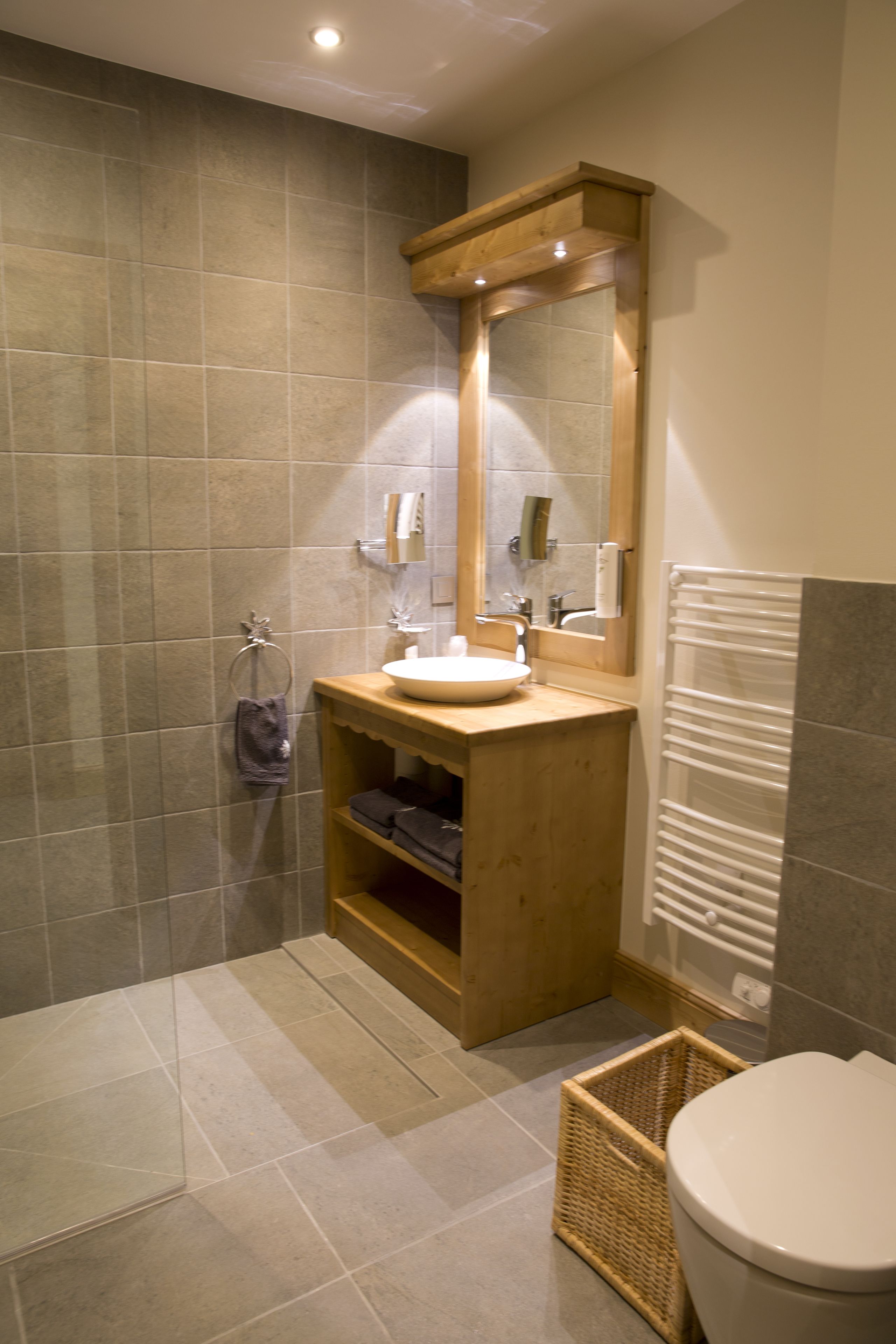 A bathroom with a wooden vanity, a sink, a mirror, and a toilet.