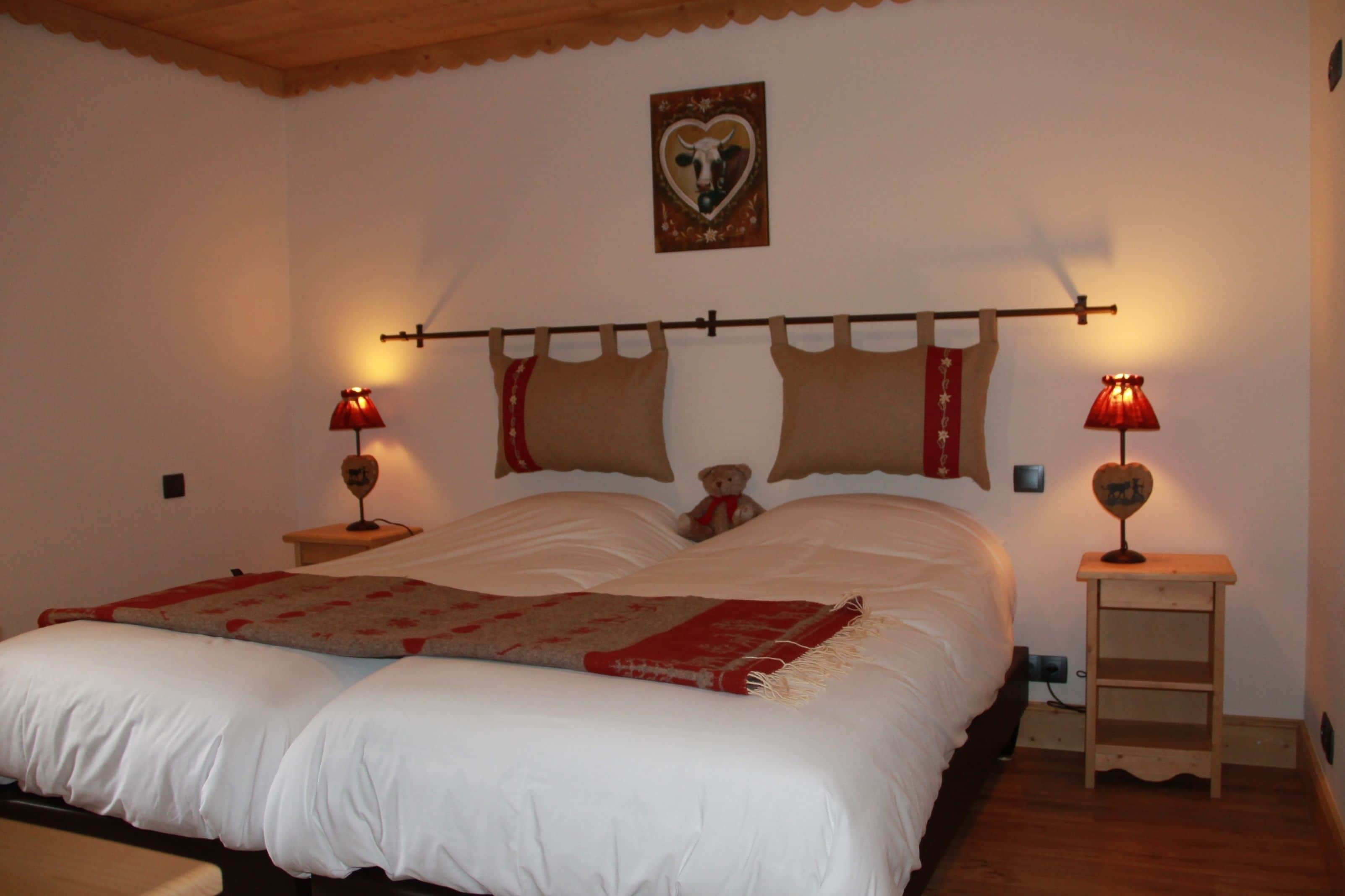 A bedroom with a large bed, two bedside lamps, a wooden headboard, and a small bedside table.
