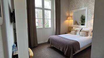 Une chambre d’hôtel avec un lit, une table de chevet, une lampe et une vue sur l’extérieur.