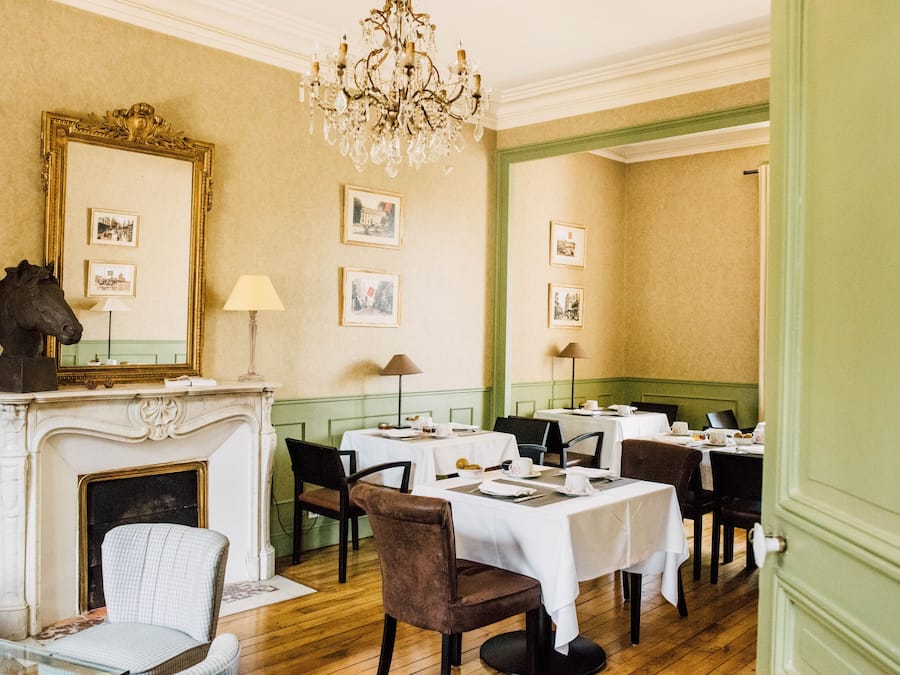 A dining area with tables set for service, a fireplace, and framed pictures on the walls.