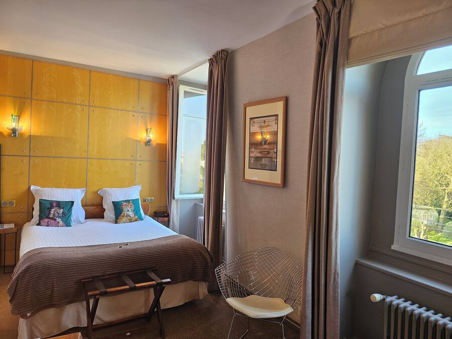 Een hotelkamer met een bed, een stoel, een radiator en een raam met gordijnen.