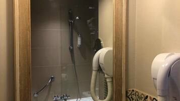 A bathroom with a large mirror, a shower, a toilet, and a hairdryer.