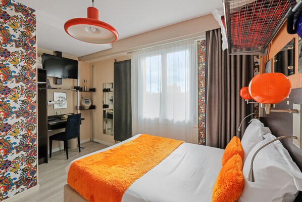 A hotel room with a bed, a desk, a chair, and a television.