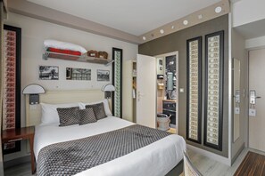 Ein Hotelzimmer mit einem großen Bett, einem Nachttisch, einem Schreibtisch und einem Kleiderschrank.