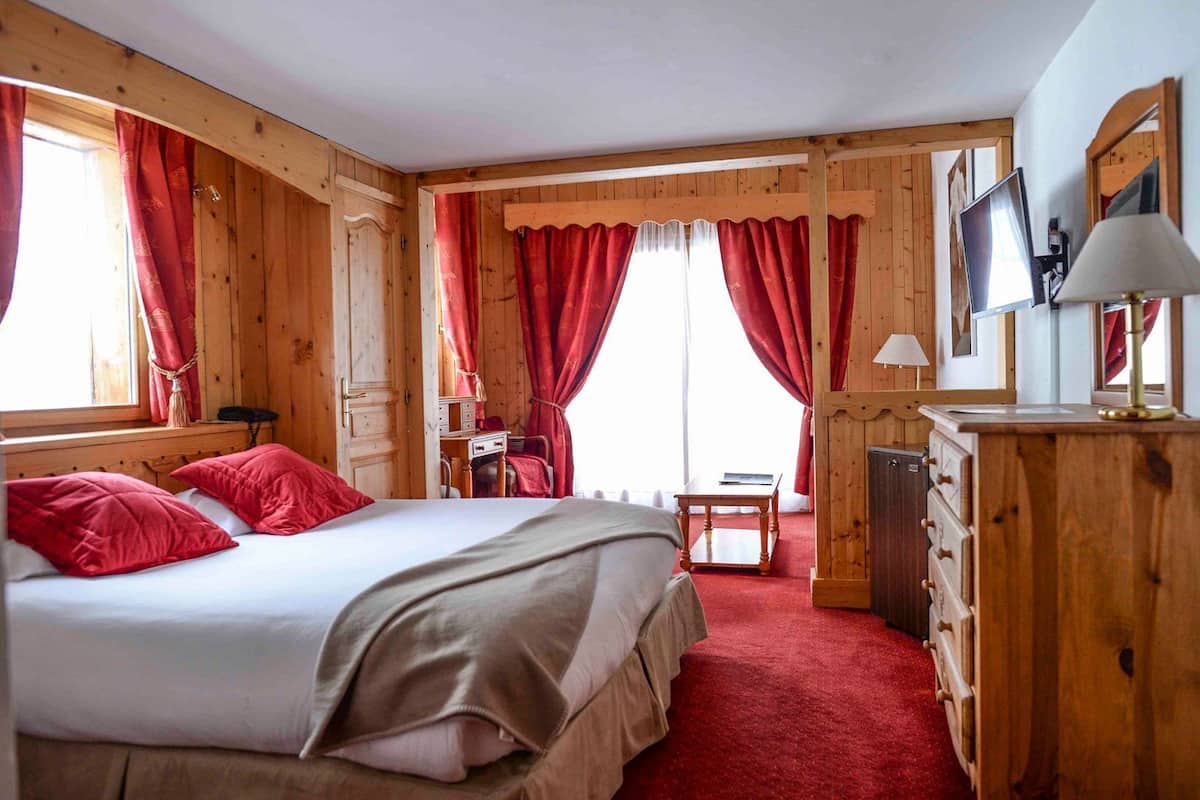 Een houten kamer met een bed, een bureau en een dressoir.