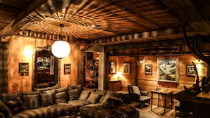 A cozy room with a wooden ceiling, a plush sofa, a bar area, and framed pictures on the walls.