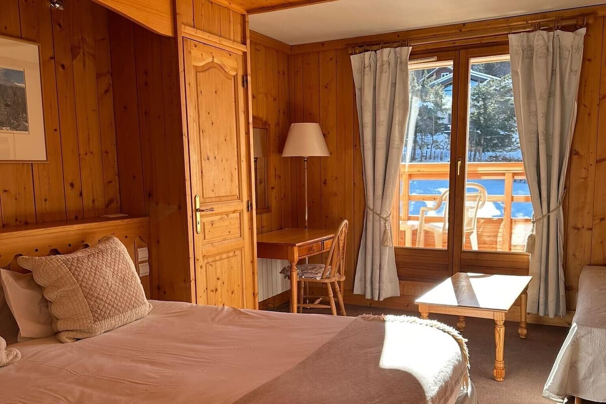 Een gezellig houten kamer met een groot bed, een bureau en een stoel.
