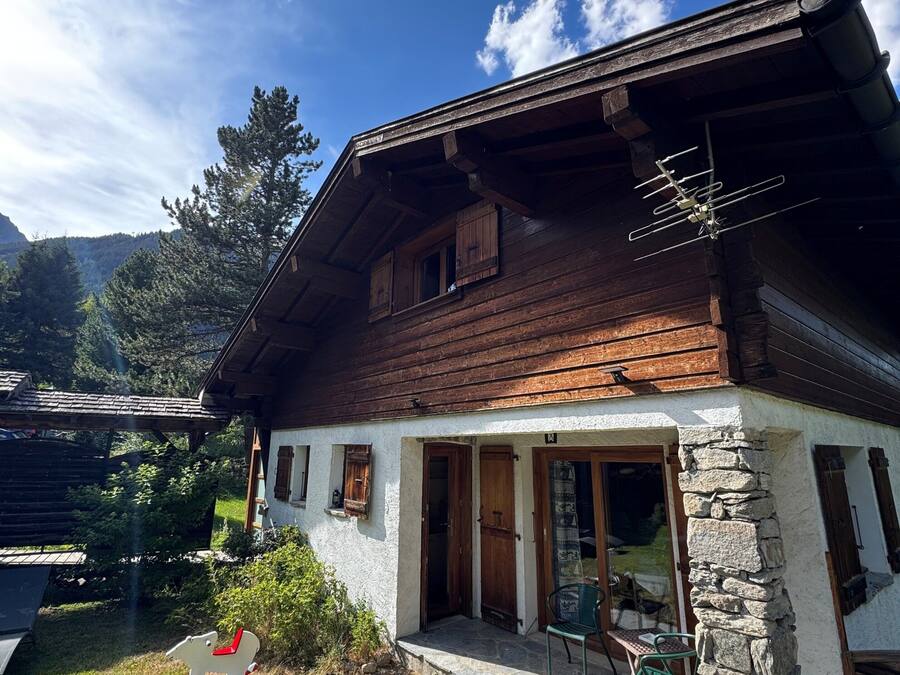 Una casa de madera con fachada de piedra, un porche de madera y un cielo despejado.