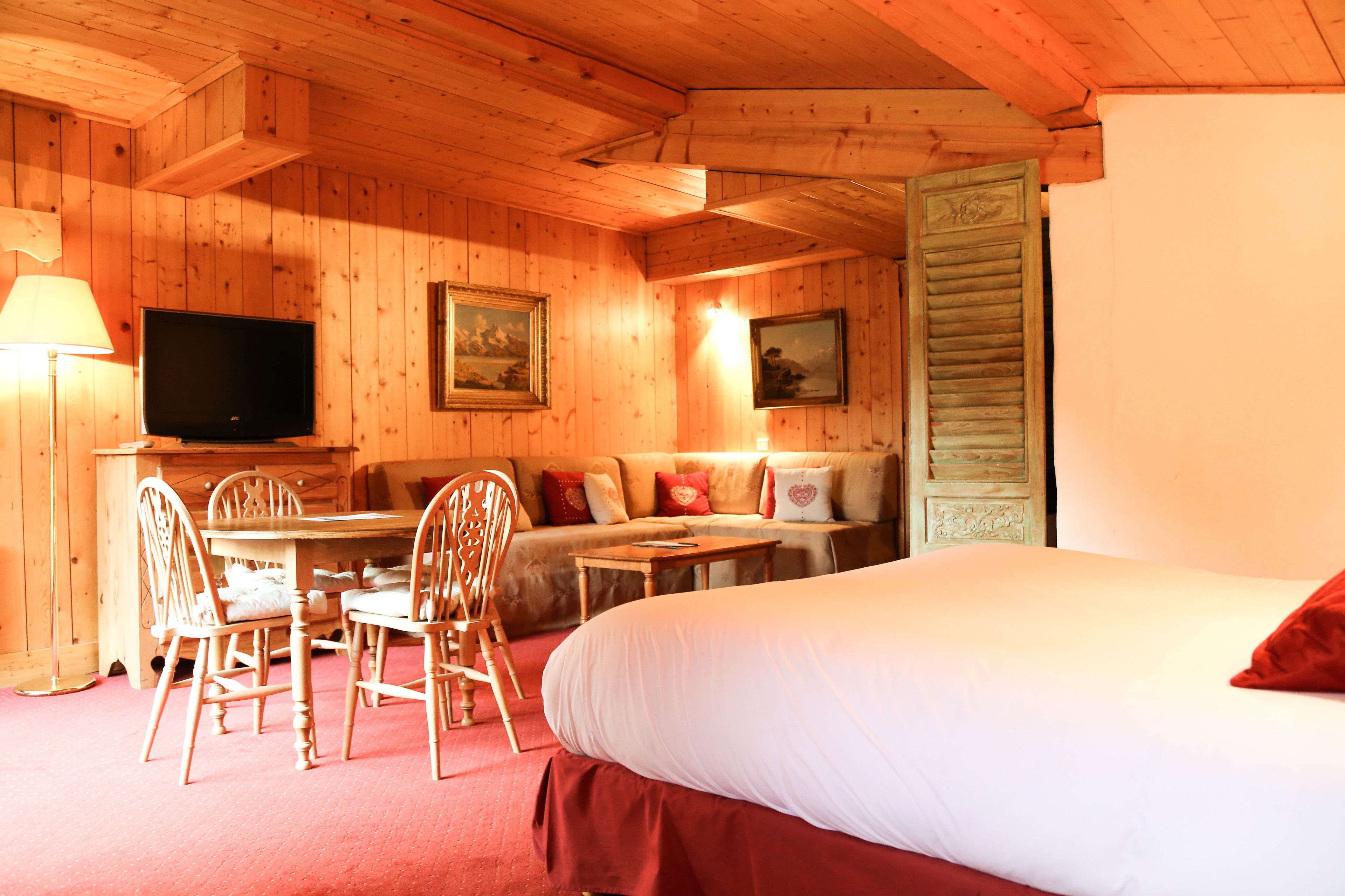 Une pièce en bois avec un lit, une télévision, un canapé, une table et des chaises.