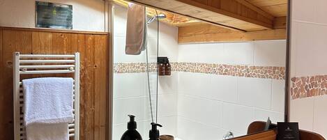 A wooden cabin bathroom with a wooden bench, a sink, a towel rack, and a mirror.