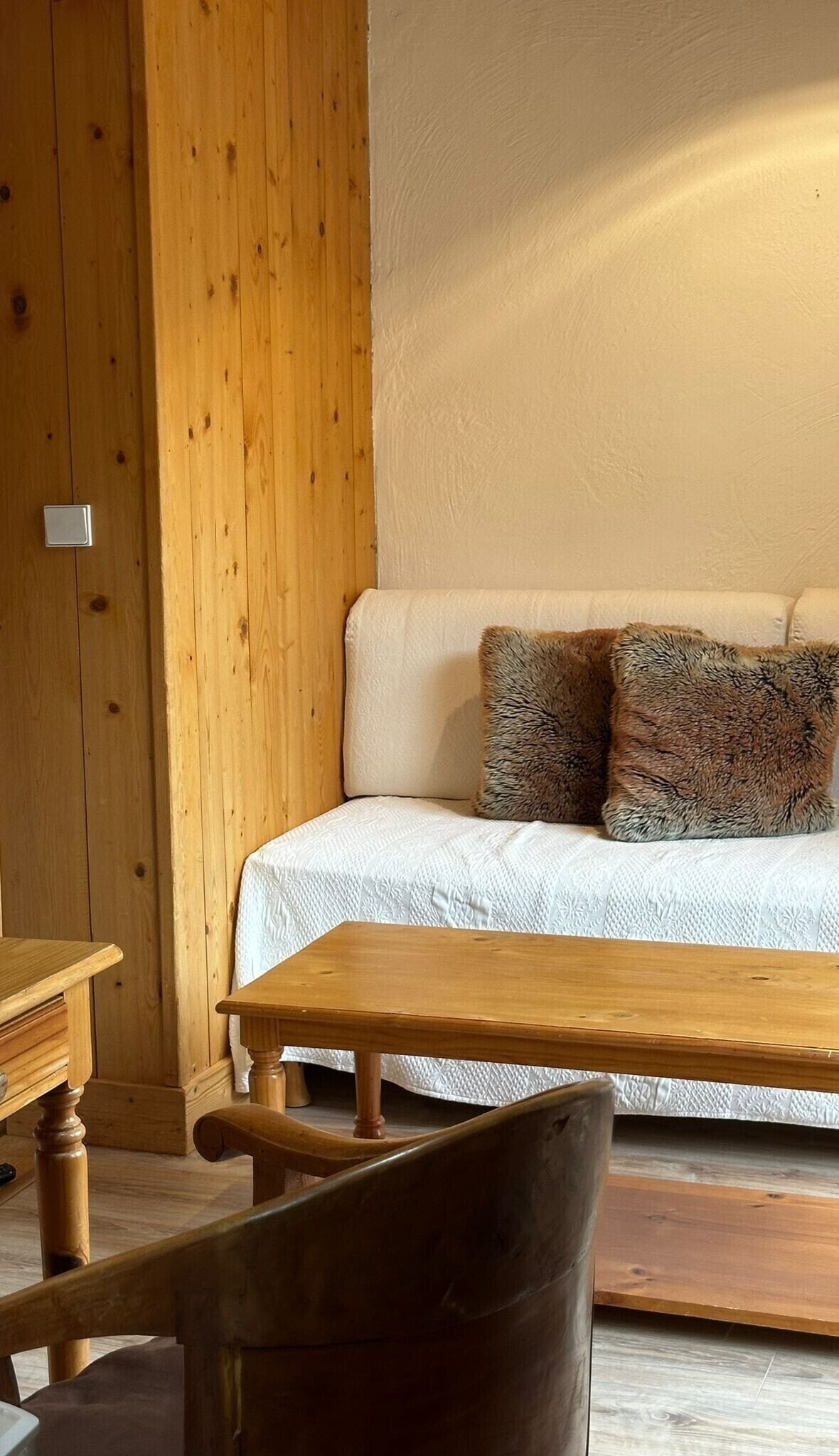 A wooden interior with a sofa, two pillows, and a wooden table.
