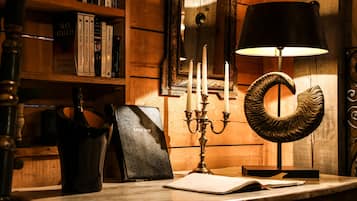 Une table en bois, ornée d’un chandelier, de livres et d’une lampe.