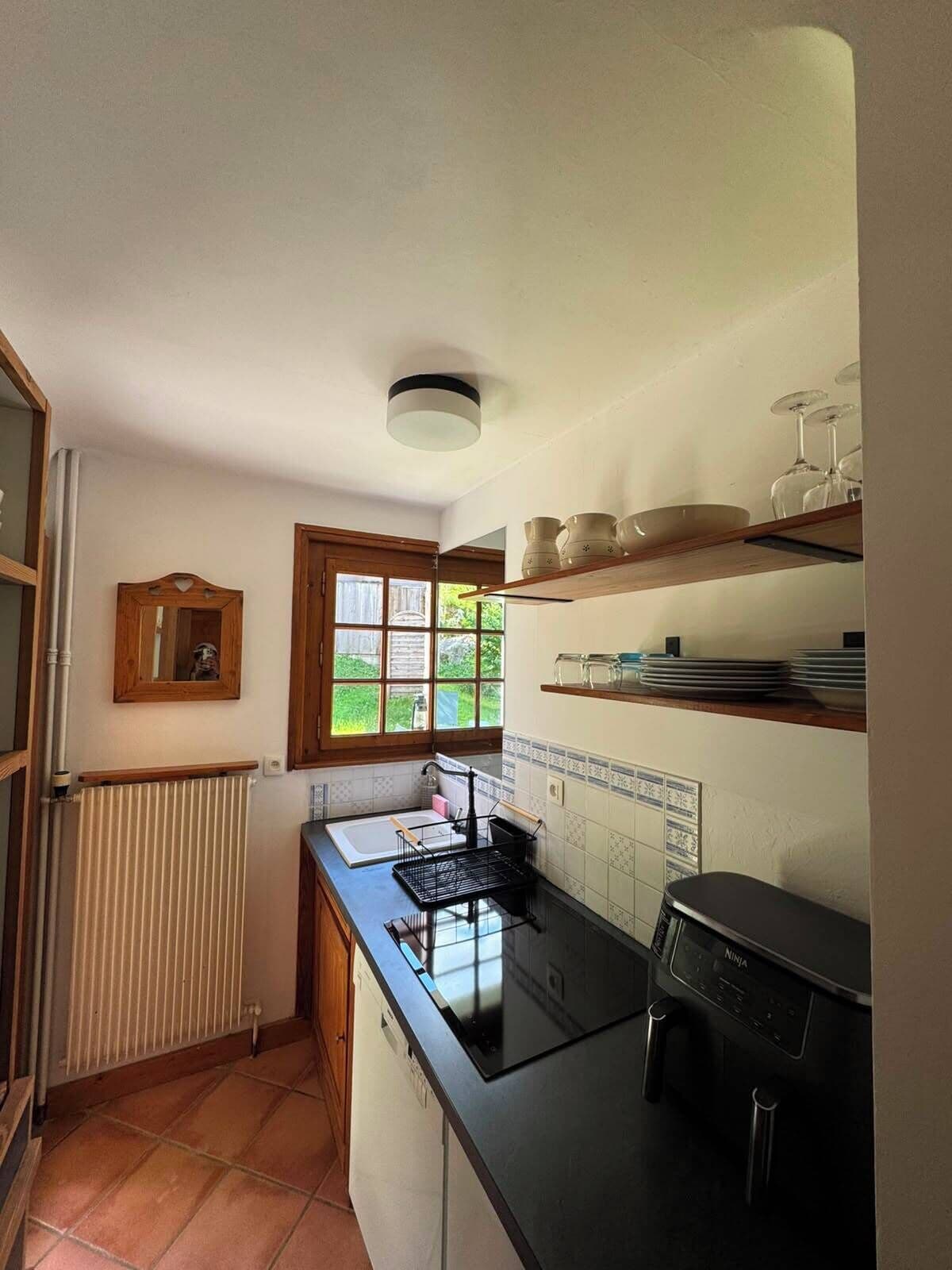 Una cocina con estufa, lavamanos y ventana.