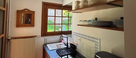 Una cocina con estufa, lavamanos y ventana.
