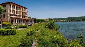 A multi-story hotel with balconies, a lawn, and a lake view. - Le Beau Rivage (Condrieu)
