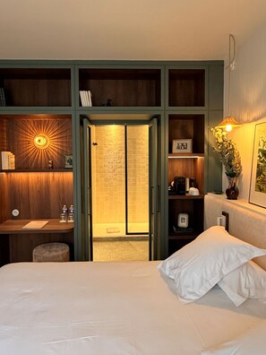 A bedroom with a bed, a desk, a wardrobe, and a bathroom with a shower.