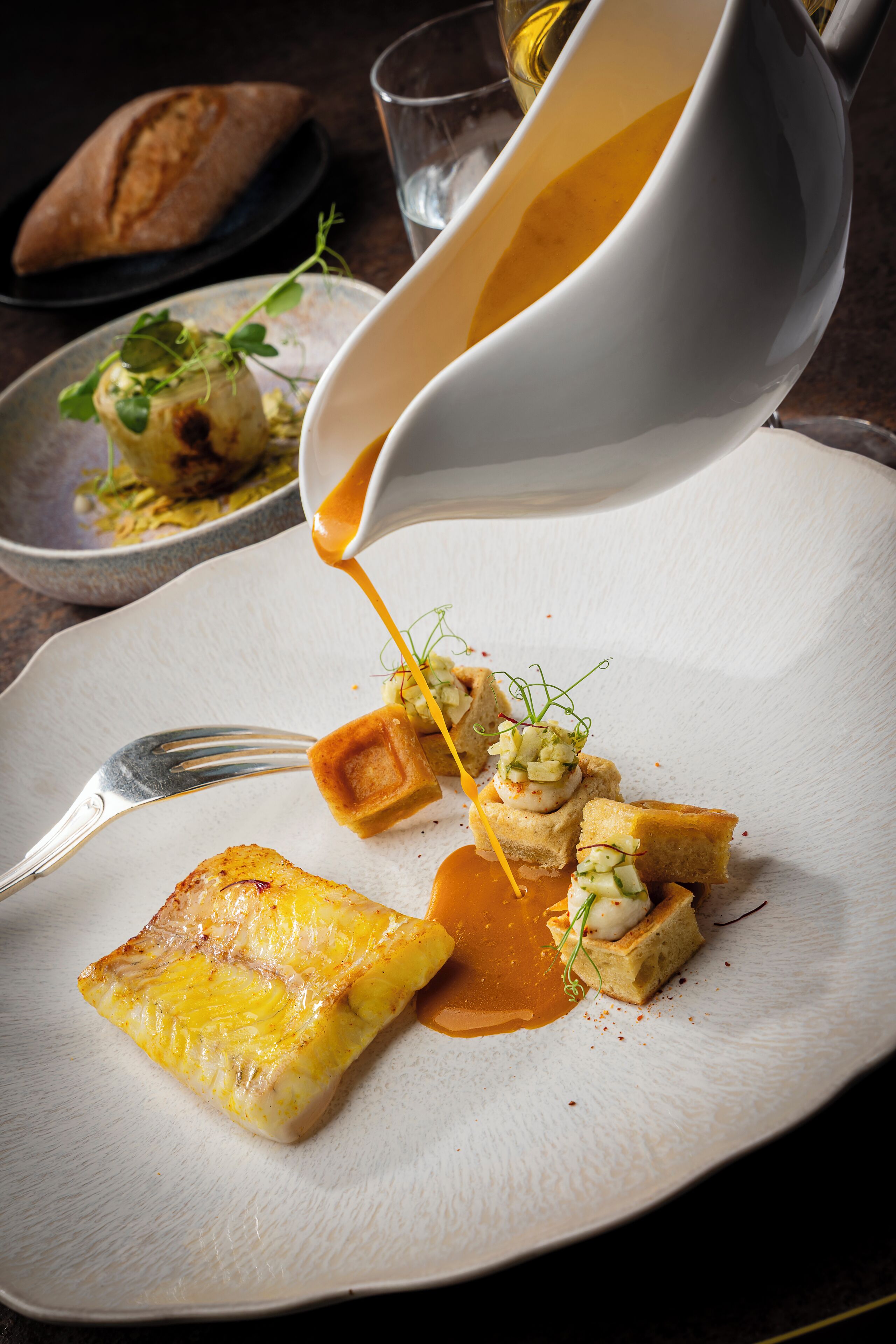 A plated dish with a sauce being poured over it.