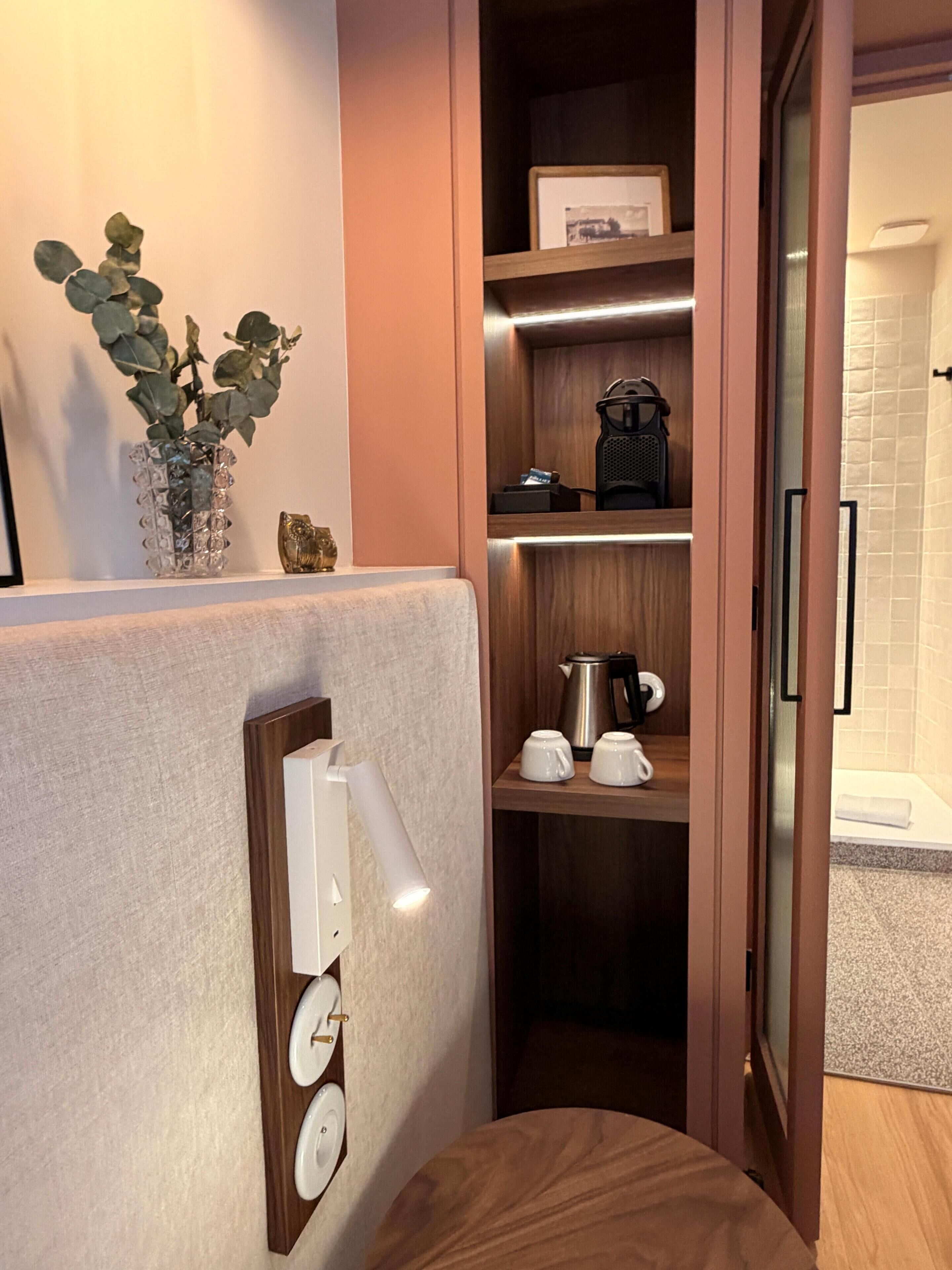 A compact bathroom with a shower, a towel rack, and a small shelf with toiletries.