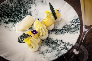A white plate with a decorative design, containing a food item and a glass.