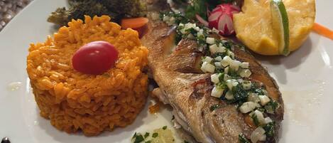 Un plato con pescado a la parrilla, arroz y verduras.