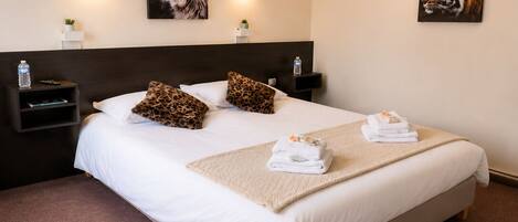 A hotel room with a large bed, two nightstands, a headboard, and wall-mounted artwork.