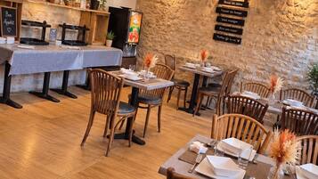 Ein Restaurantinneres mit Holzboden, gedeckten Tischen und einem farbenfrohen Deckengestaltung.