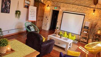 A cozy room with a stone wall, a whiteboard, a projector screen, and comfortable seating.