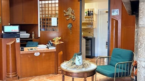 A reception area with a wooden desk, a computer, a seating area with a chair, and a decorative lion sculpture.