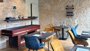 A restaurant with a stone wall, wooden bar, and colorful ceiling.