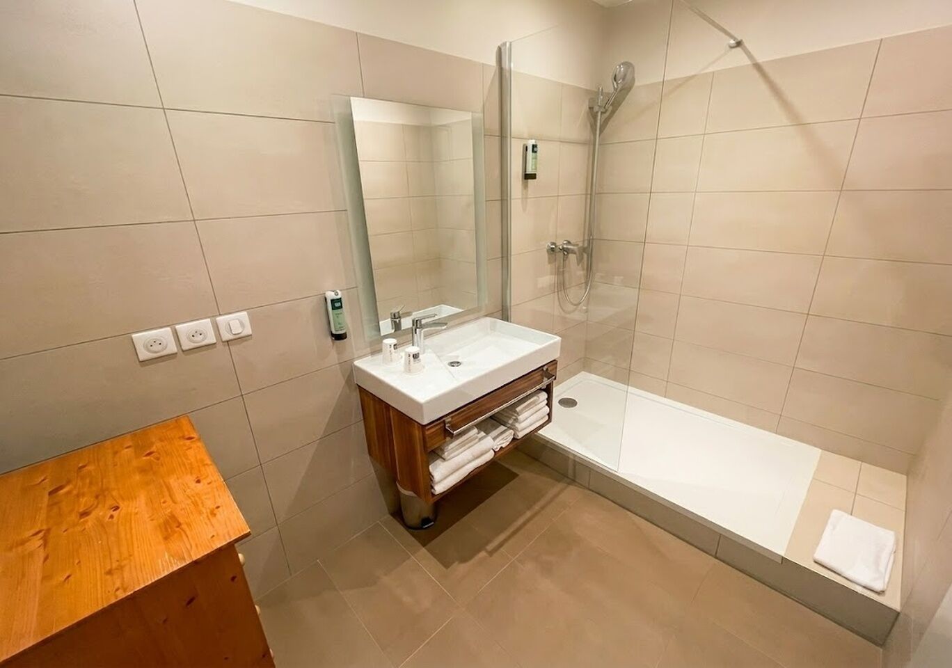 A modern bathroom with a glass-enclosed shower, a wooden vanity, and a large mirror.