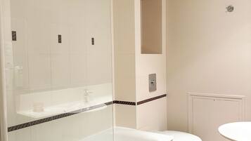 A modern bathroom with a glass-enclosed shower, a white bathtub, a toilet, and a sink.