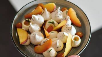 A hand holding a bowl of food with various fruits and a white creamy substance.