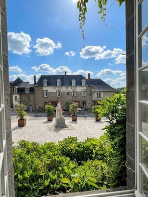 A courtyard with a statue, potted plants, and a building labeled 'HOTEL DU LAC RESTAURANT.' - Logis Hotel du Chateau (Combourg)